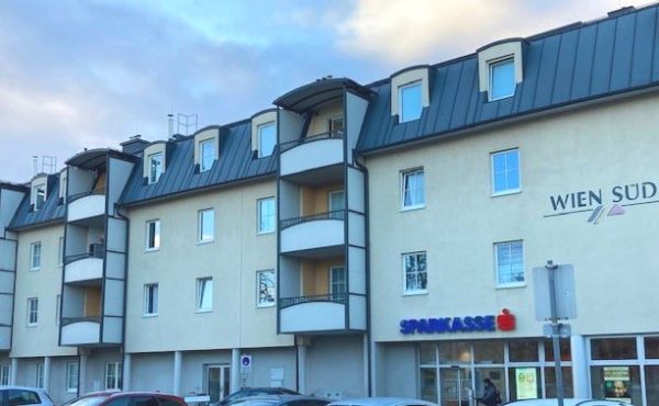 Wohngebäude mit Geschäften im Erdgeschoss, sonniger Himmel, moderne Architektur, Wien Süd und Sparkasse.