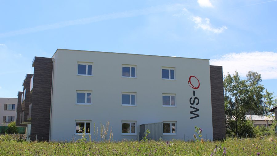 Modernes Wohngebäude mit weißen Wänden, hellblauer Himmel im Hintergrund.