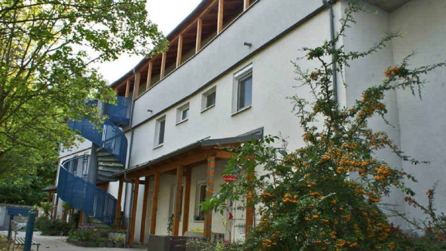 Moderner Gebäudekomplex mit blauer Wendeltreppe und umgebender grüner Vegetation.