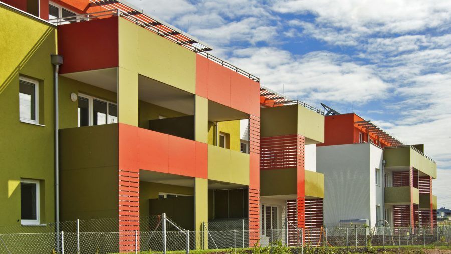 Moderne bunte Wohngebäude mit Balkonen und klarer Architektur unter blauem Himmel.